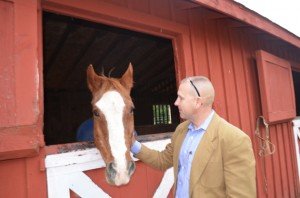 Tom Russell pets one of the horses bordering at Silver Eagle Stable. 