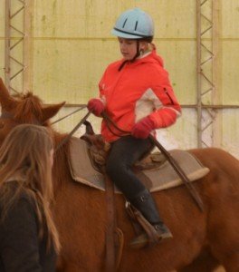 Girl in orange begins to lead her horse in the arena. 