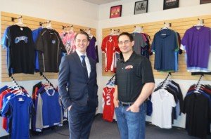 Owners/Operators Jeff Mayhugh and Chris Concepcion stand inside their new showroom with sample apparel behind them. 