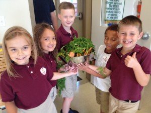 Bristow Montessori students show off vegetables grown in their garden. 
