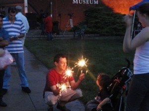 Dad shows off sparklers to child outside of the Manassas Museum. 