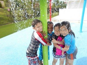 Primrose summer students play under the sprinkler on the Bristow Primrose School playground.  