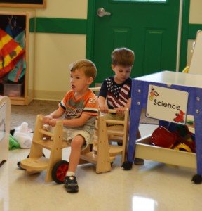 Older toddlers ride wooden scouters during summer camp. 