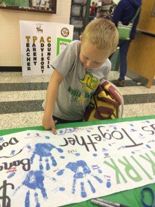 Glenkirk student Michael Baxter signs the poster with his thumbprint. 