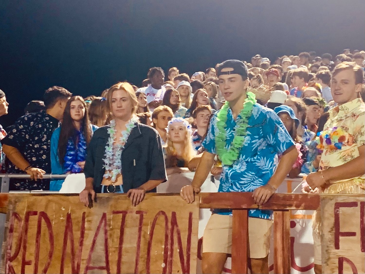 Current Patriot High School students and alumni join "Red Nation" cheering on the Patriots at their 10 year celebration game. The theme of the night was Hawaiian or tropical dress.