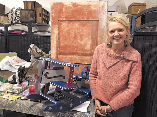 Artist Carole Scoggin poses with a child’s rocker she turned into a bi-plane. She “rescues” old furnishing at her home-based Nockamixon Township business, Red Door Redo. Photograph by Kathryn Finegan Clark.