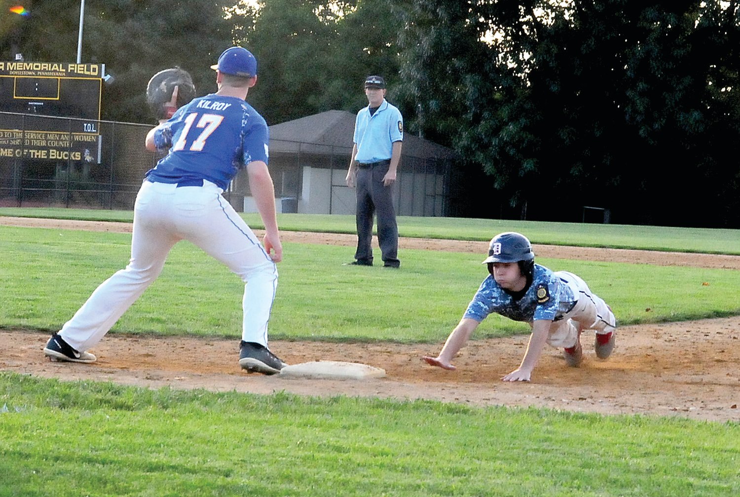 Doylestown Post 210 pinch runner Matt Mannino, right, dives back to first base in the Tigers’  June 21 Bux-Mont American Legion League battle with Perkiomen. David Kilroy, No. 17, left, covers the bag for Post 184.