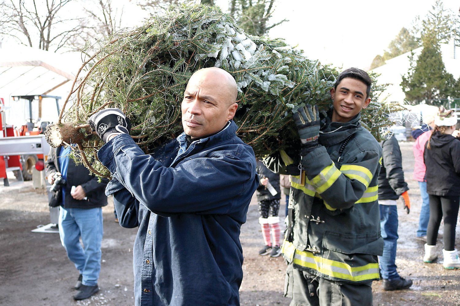 Michael Soriano, the mayor of Parsipanny, N.J. (front), and an unidentified volunteer firefighter help load Christmas trees for Trees for Troops into a Federal Express truck.