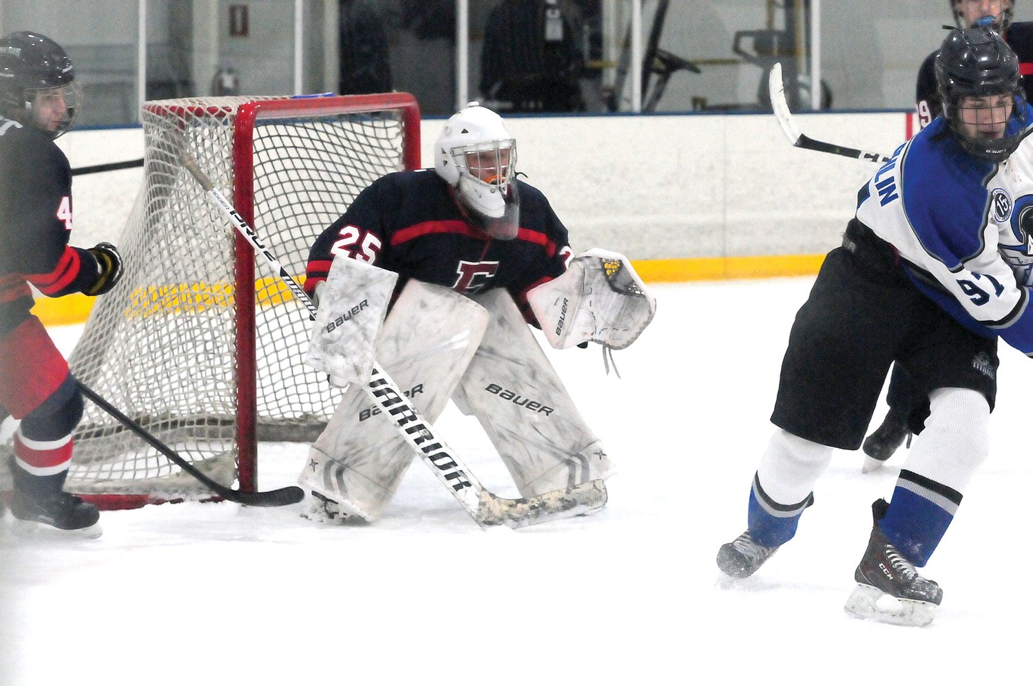 CB South forward Harry McLaughlin, 97, right, works the puck across ice as CB East goalkeeper Chris McIntyre stands tall between the pipes in the Titans’ win over the Patriots Jan. 8. Photograph by Steve Sherman.