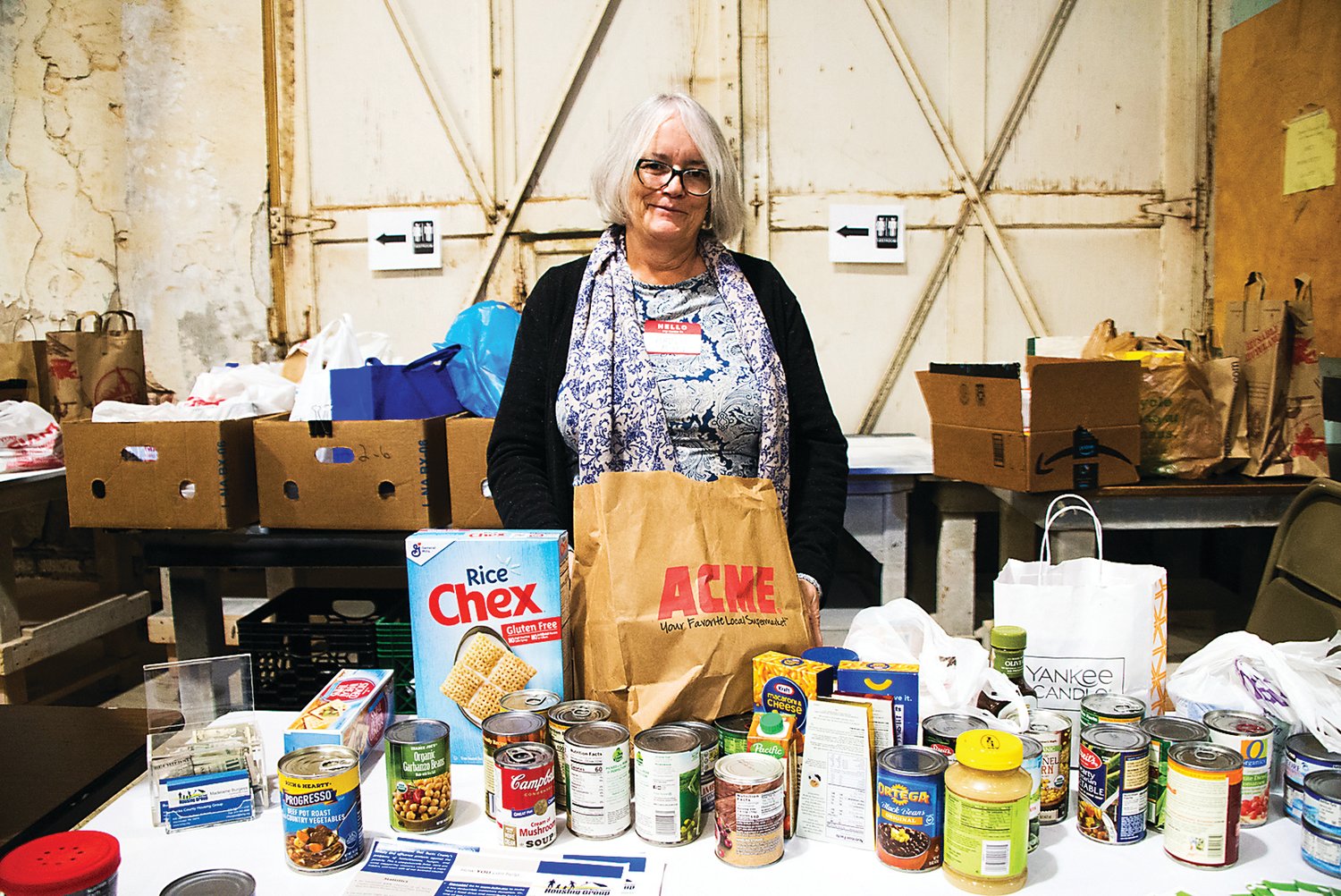 Maddie Burgess, Bucks County Housing Group community food pantry manager, accepts the donations of the attendees of Locavore. More than 2,000 pounds of food was donated to the Bucks County Housing Group based in Warminster. Photograph by Chiara Chandoha.
