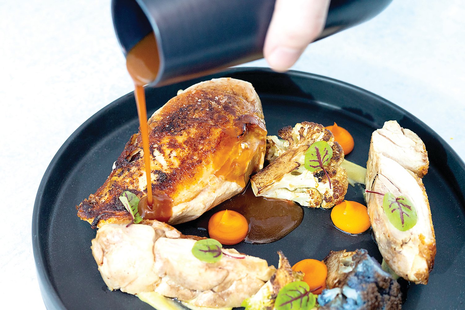 Sherry chicken jus is poured over an order of roasted chicken at Solstice, Newtown’s newest upscale dining venue. Photograph by Solstice.