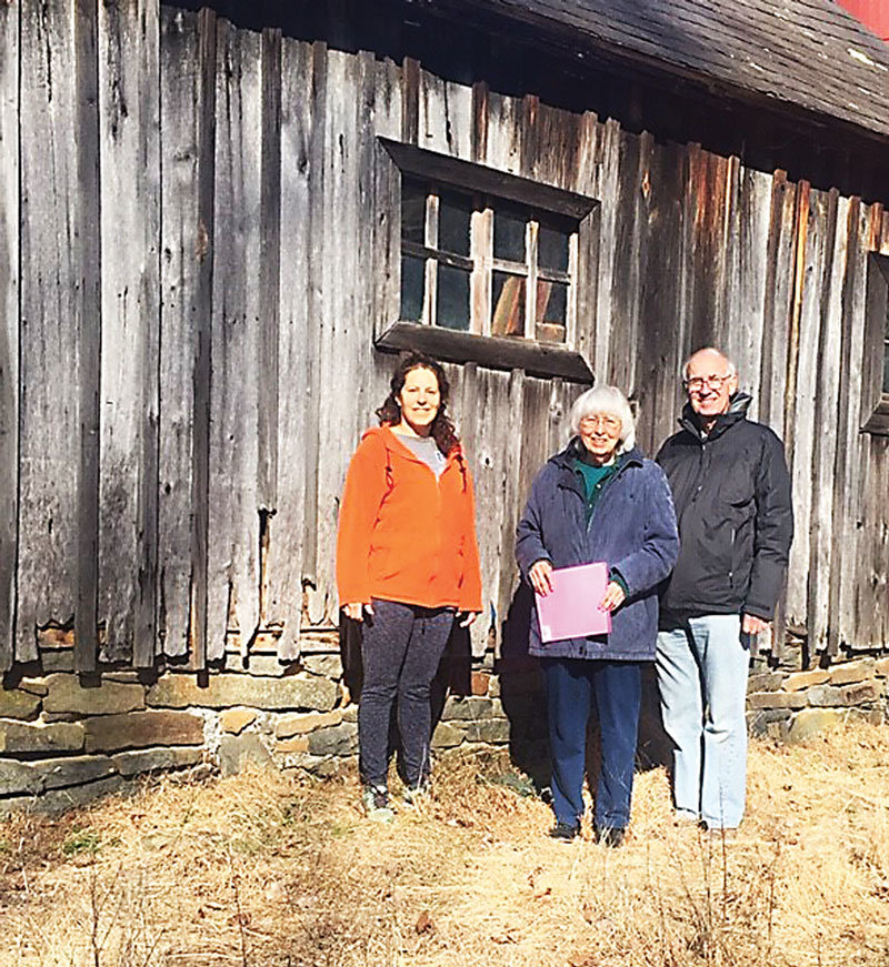 Visiting the old Bryan Cemetery in Haycock Township are, from left, Rachel Isaac, Marjorie Fulp, Haycock historian, and her husband, Charles Fulp. Part of the original stone wall for the burial ground is now the foundation of the barn. Photograph by Kathryn Finegan Clark.
