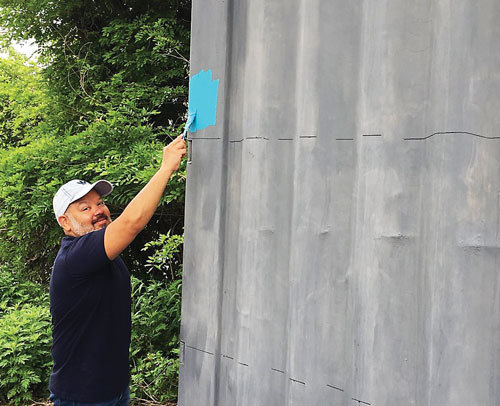 Artist Marlon Davila begins painting the D&R Greenway mural at Bordentown Beach.