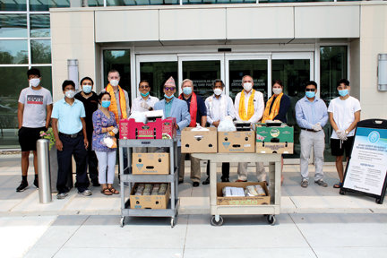 Members of the PA Nepalese Guthi Association and their family members present meals to Doylestown Health President and CEO Jim Brexler, center with red scarf, and Vice President and Chief Development Officer Laura Wortman, third from right. U.S. Rep. Brian Fitzpatrick, fifth on left, also joined the group at the entrance of the Cardiovascular and Critical Care Pavilion on the Doylestown Hospital campus.