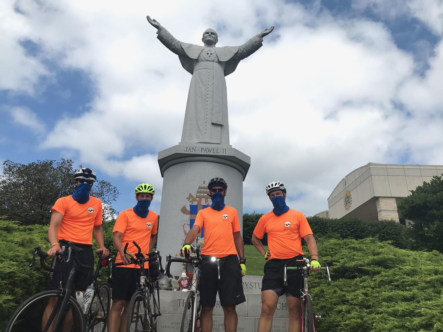 The Perimeter Route bikers take a moment in front of the statue of Pope Saint John Paul II at the National Shrine of Our Lady of Czestochowa in Doylestown. They are, from left, Dominic Mirenda, Chris Massaro, the Rev. Chris Cooke and Tucker Brown.