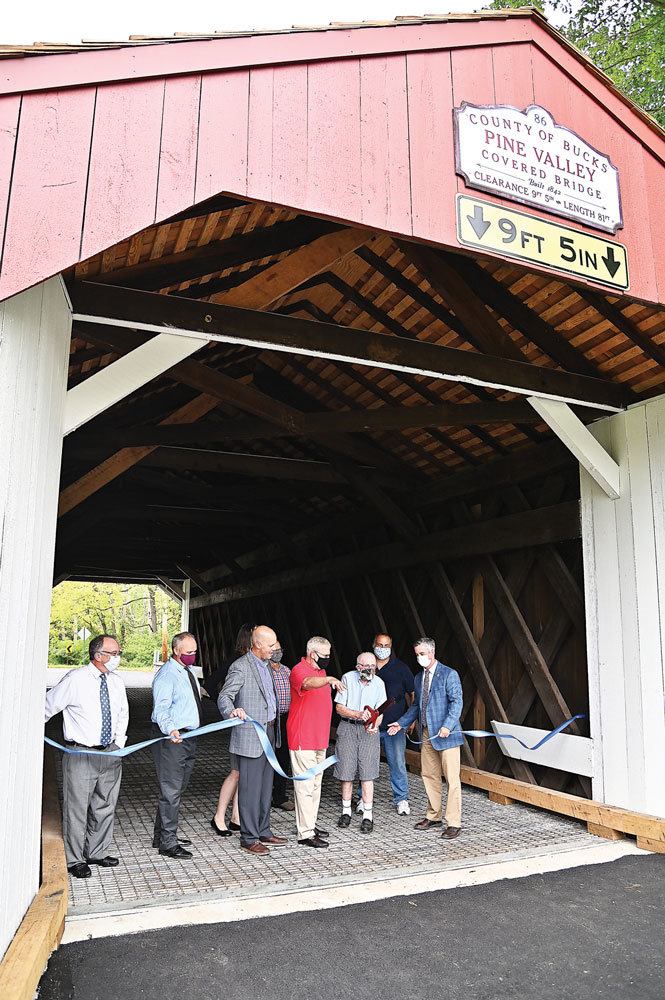 Participants in the ribbon-cutting for the reopening of the Pine Valley Covered Bridge included, Samantha Bryant, New Britain Borough manager, partially hidden, third from right; Kevin Spencer, Bucks County general services manager; Steven Ascher, New Britain Borough Council member; David Holewinski, New Britain Borough mayor; Bruce Burkart, New Britain Borough historian; an unidentified participant; and Bob Harvie, Bucks County commissioner.