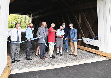 Participants in the ribbon-cutting for the reopening of the Pine Valley Covered Bridge included, Samantha Bryant, New Britain Borough manager, partially hidden, third from right; Kevin Spencer, Bucks County general services manager; Steven Ascher, New Britain Borough Council member; David Holewinski, New Britain Borough mayor; Bruce Burkart, New Britain Borough historian; an unidentified participant; and Bob Harvie, Bucks County commissioner.