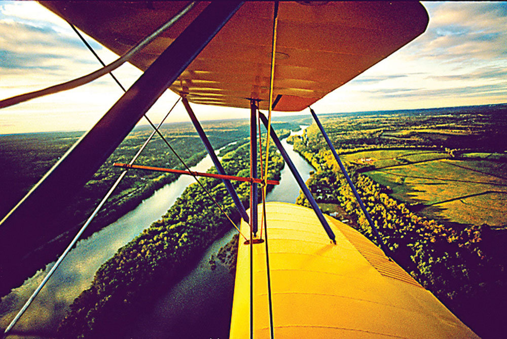 “Bi-Plane Over River” is a digital photograph by H. Scott Heist.