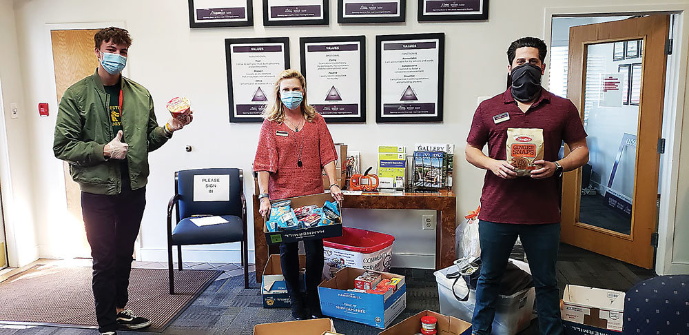 Sales associates and employees of Berkshire Hathaway HomeServices Fox & Roach’s Doylestown office stand with goods collected for A Woman’s Place.