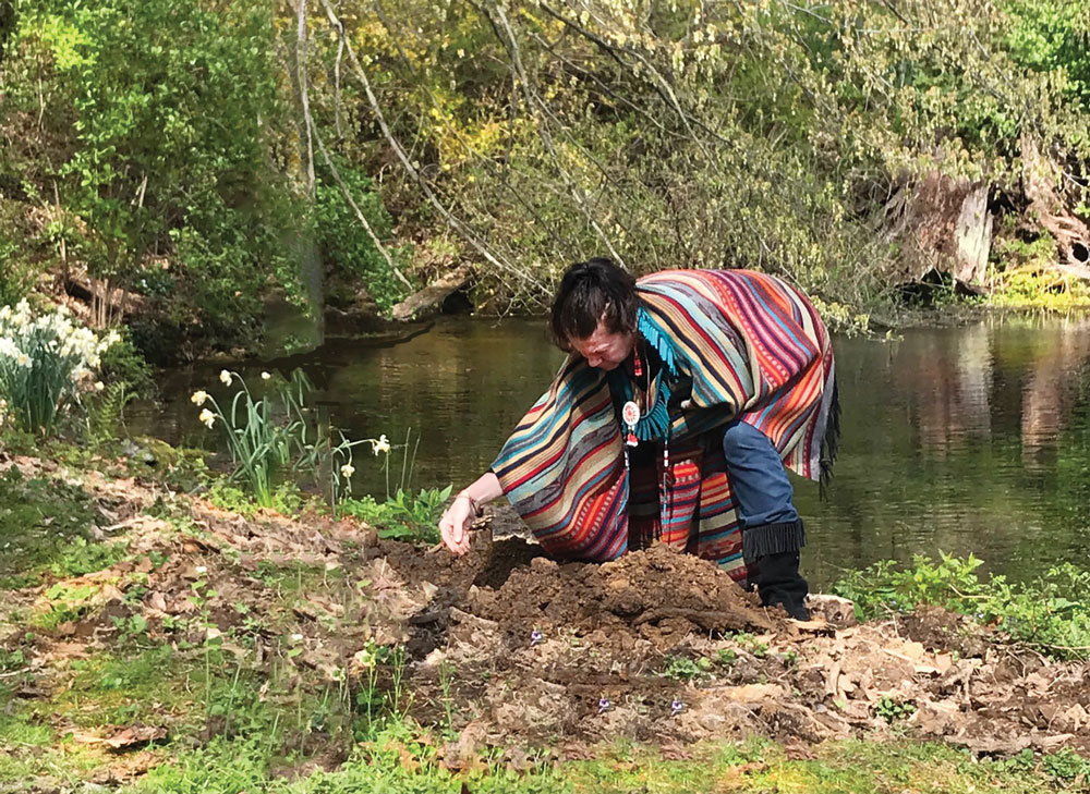 Barbara Bluejay Michalski prepared the earth for planting of an eastern red cedar tree next to Aquetong Spring. The tree replaces a decayed cedar that had been planted by her grandfather, Chief Whippoorwill, Bill Thompson, three decades earlier. (Nancy Stock-Allen)