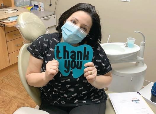 A grateful HealthLink patient holds up a sign for Encore Rides, the sponsor of the day’s no-cost dental services.