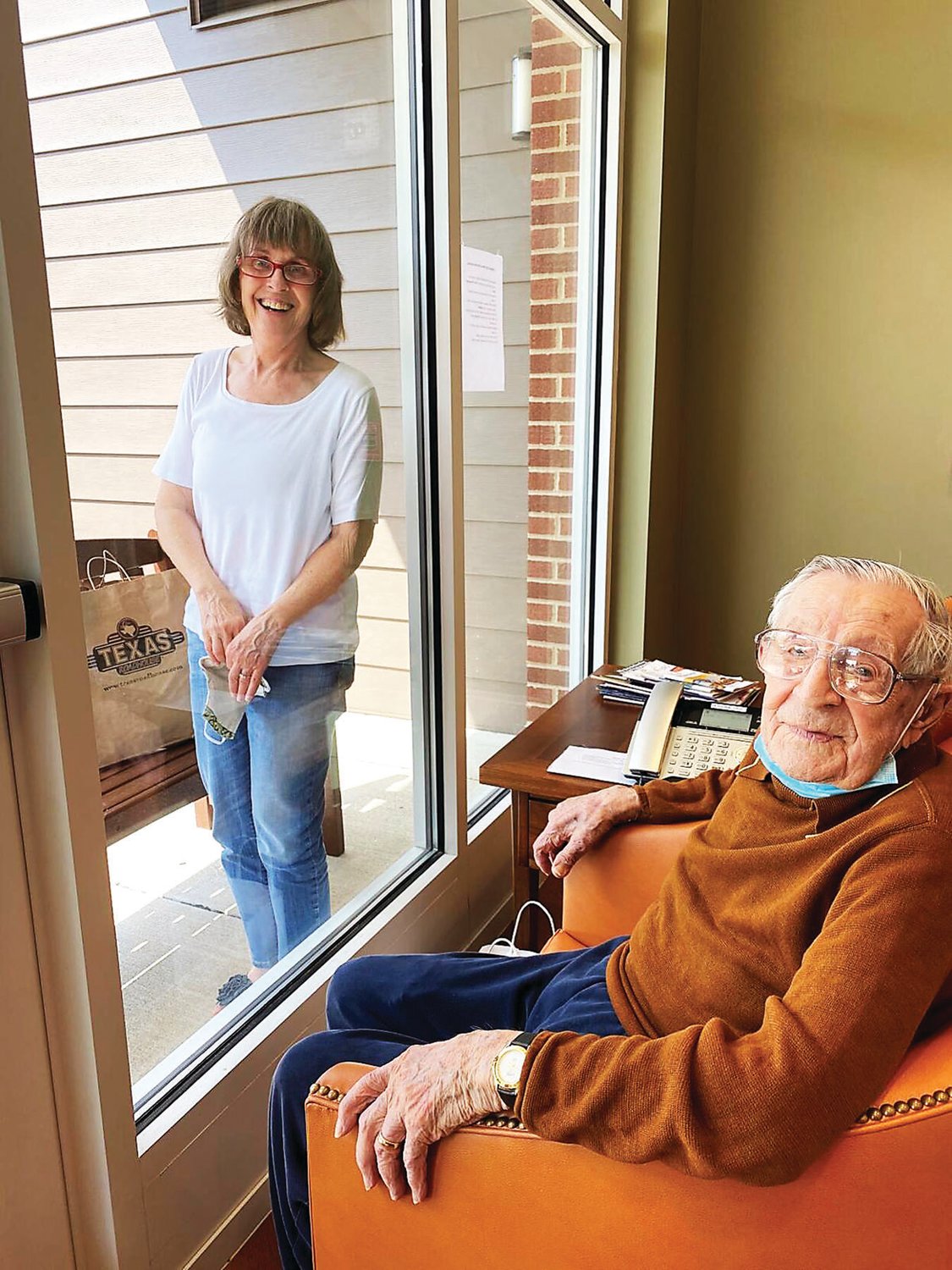 Yvonne Caputo and Joe Haenn visit through the window of the personal care community where he resides.