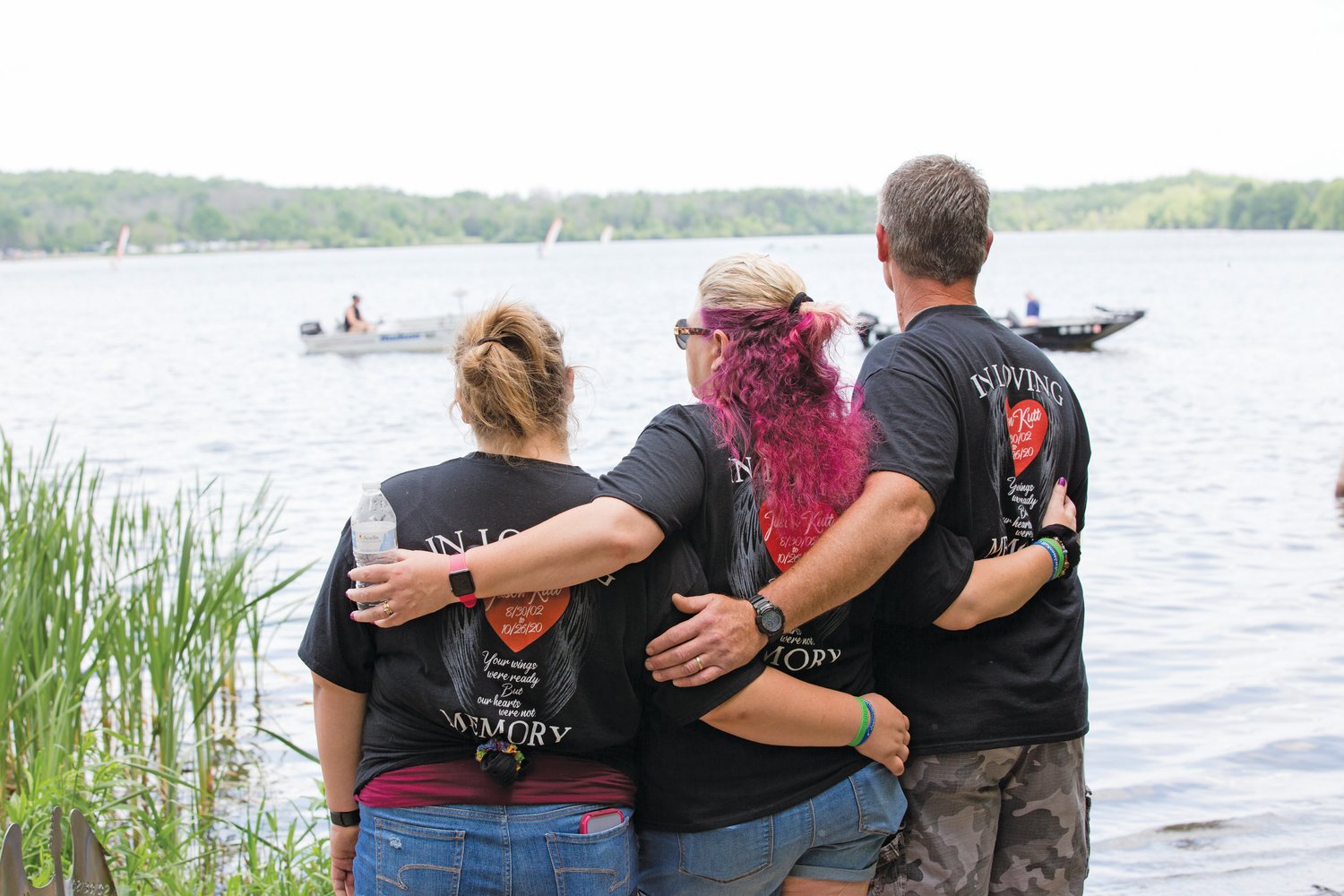 The family of Jason Kutt, an 18-year-old Sellersville resident who was fatally shot at Lake Nockamixon last October, watch a parade of boats pass by the site of a memorial bench that was dedicated in his honor on Sunday. The boats, as they passed by the shore, played one of Kutt’s favorite songs by the band Metallica. From left are Kutt’s sister, Brianna Hill; his mother, Dana Kutt; and his father, Ron Kutt.