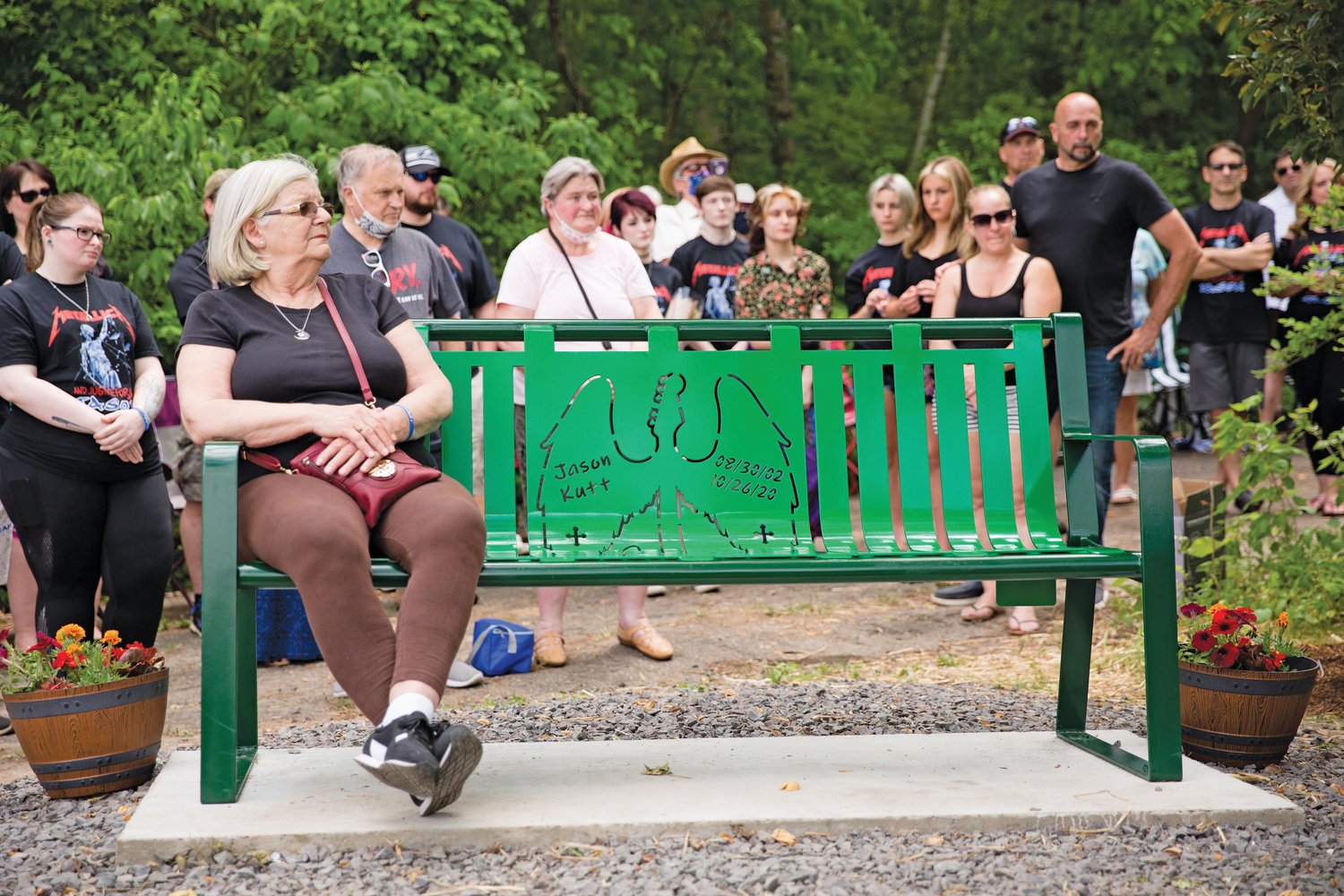 Family and friends of Jason Kutt, who was fatally shot at Lake Nockamixon last October, attend the dedication of a memorial bench created in his honor. Sitting on the bench is Toni Palmer of Perkasie, Jason’s grandmother.