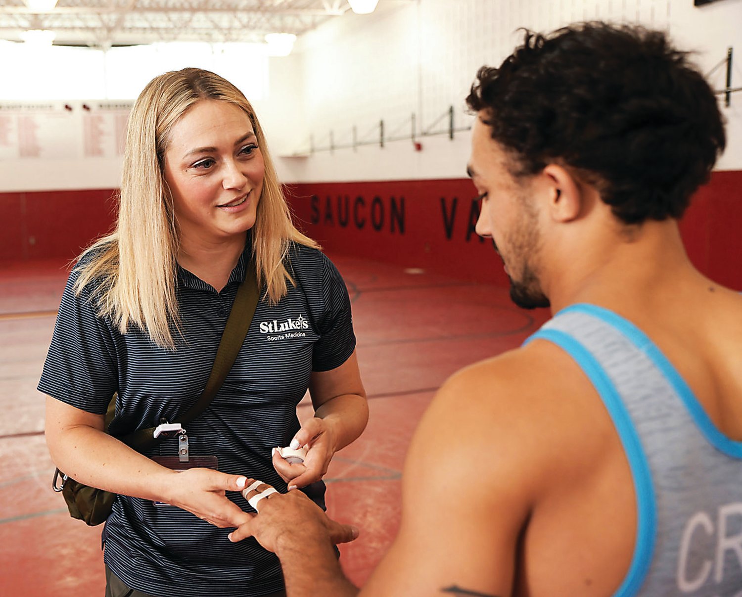 Shelby Hoppis, lead athletic trainer for St. Luke’s University Health Network, tapes the fingers of wrestler Darian Cruz of Allentown.