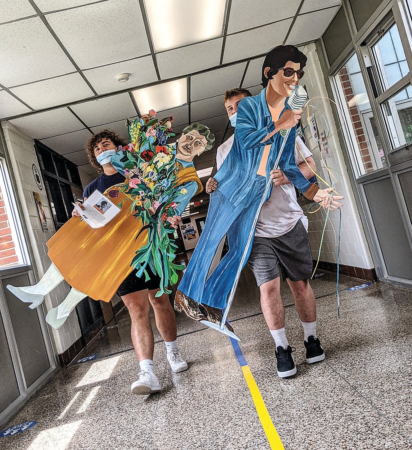 Cutouts of innovative floral designer Constance Spry (1886-1960) and gay and lesbian rights activist Jeanne Cordova (1948-2016) are delivered to classrooms by students Scott Pursell, left, and Tim Torrey.