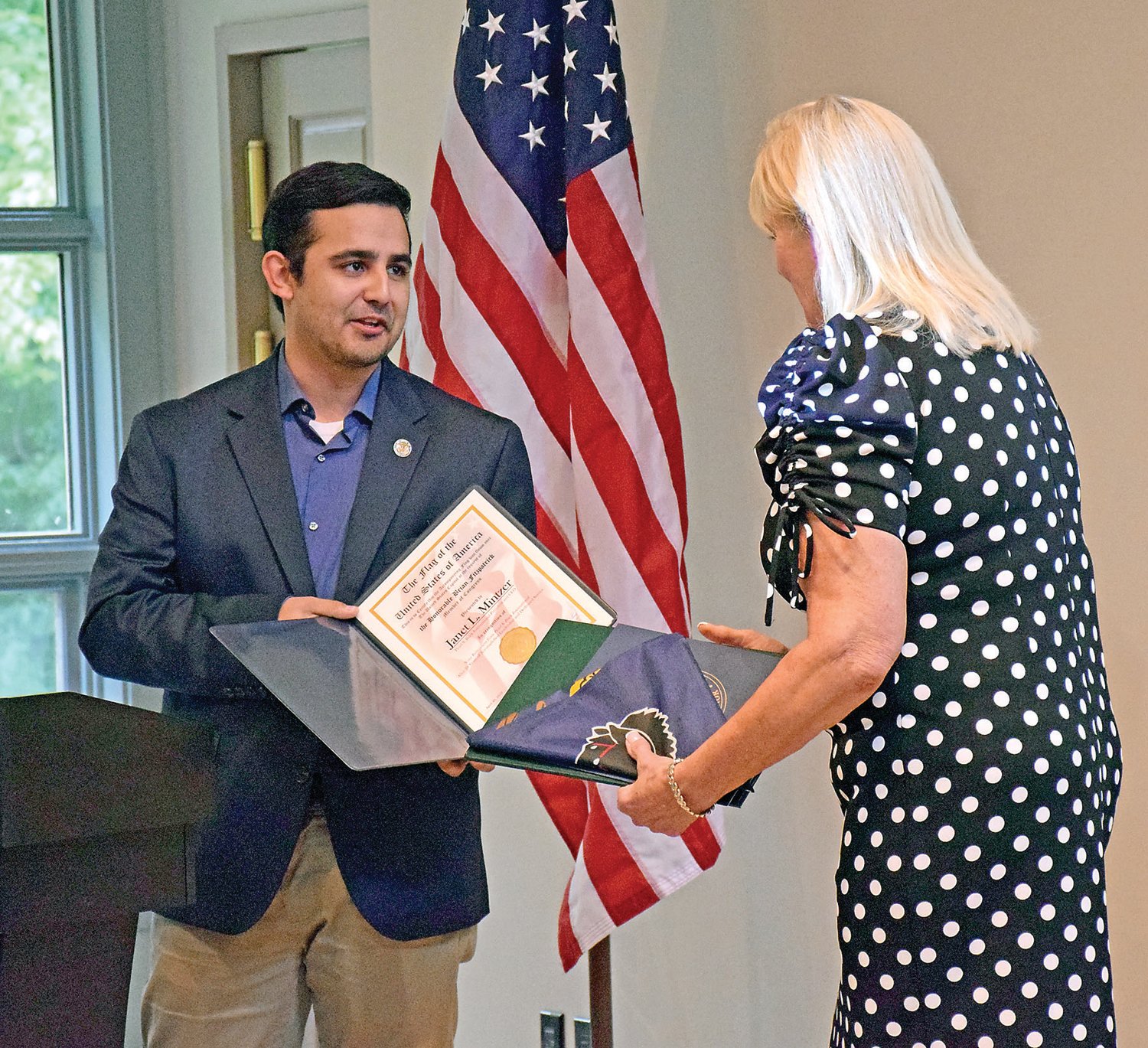 On behalf of U.S. Rep. Brian Fitzpatrick, Ryan Oister gives a certificate of achievement to Janet L. Mintzer.