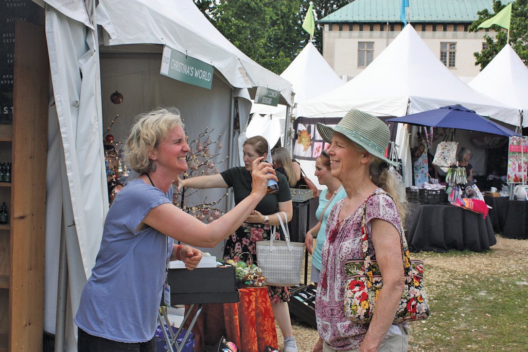 Linda Shanahan, co-owner of Barefoot Botanicals in Doylestown with Eric Vander Hyde, sprays JoAnne Fogelman of Turbotville, Northumberland County, formerly of Souderton, with a cooling rose geranium hydrosol spray.