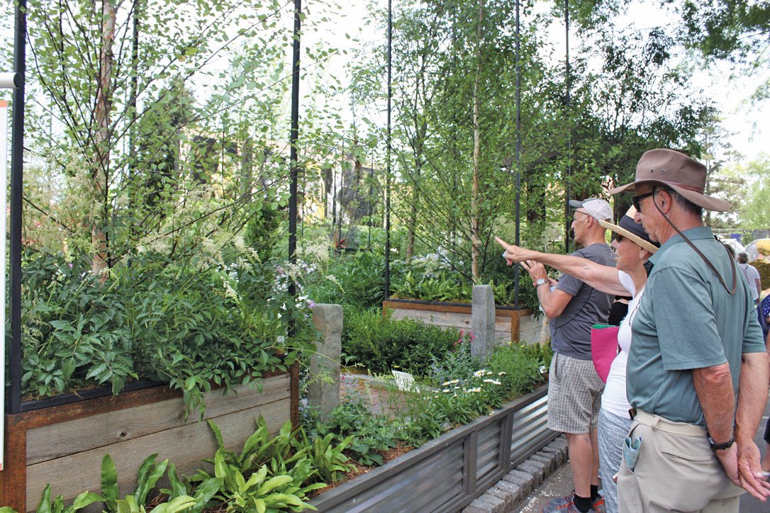 A flower show visitor points out one of the plants in “Intertwined” by Mark Cook Landscape and Contracting of Doylestown.