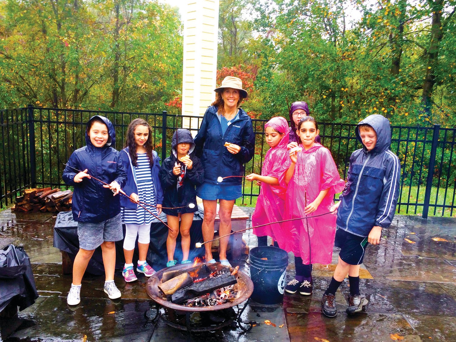 Patricia Walsh-Collins, founder and director of Earth School, roasts marshmallows with children during a rainy day outside.