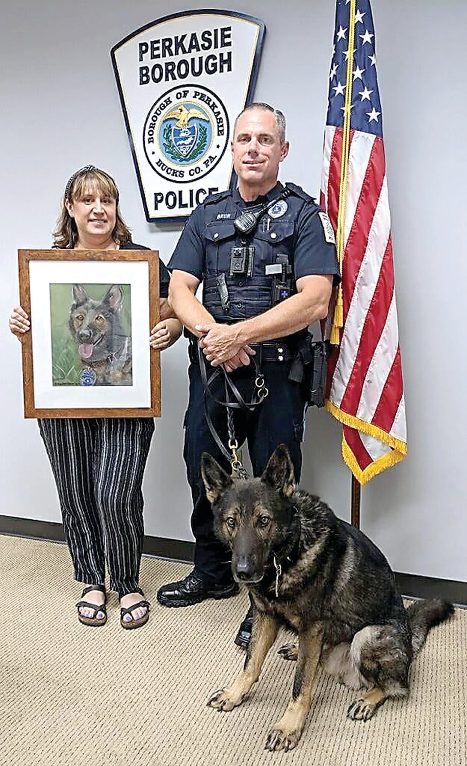 Perkasie K-9 Revo, with Officer Tom Brun, poses with his portrait, held by local artist Randi Kopelow.