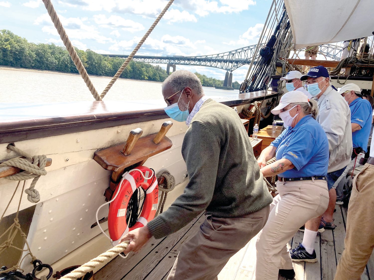State Sen. Art Haywood, left, helps raise the sails on the tall ship.