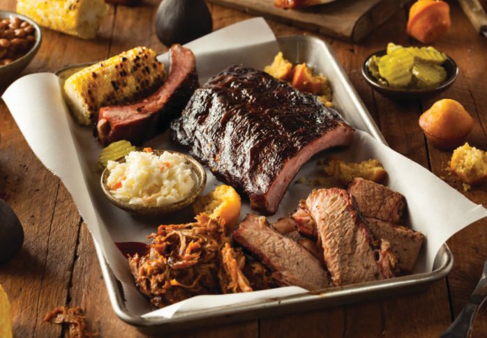 A meat platter with sides at Holy Que Smokehouse in Lahaska features a variety of Texas barbecue meats.