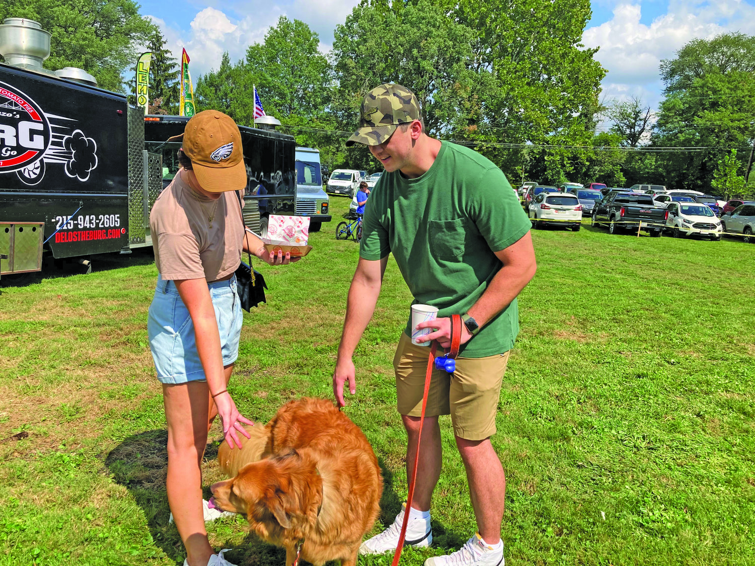 Cassie Baner, left, and Matt Raczak enjoy some food and drink and their golden retriever Finn during Harvest Day in Yardley Borough.