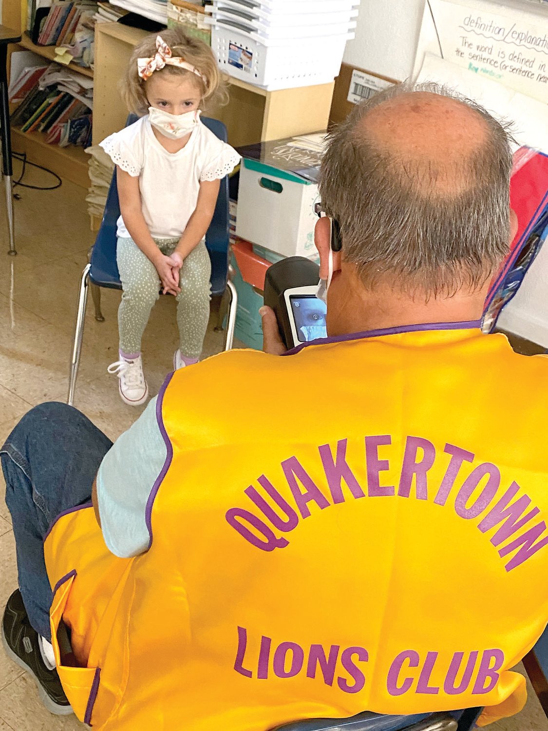 Marty Mack and Diane Williams of the Quakertown Lions Club provide an ear exam on Mia, St. Isidore School preschooler.