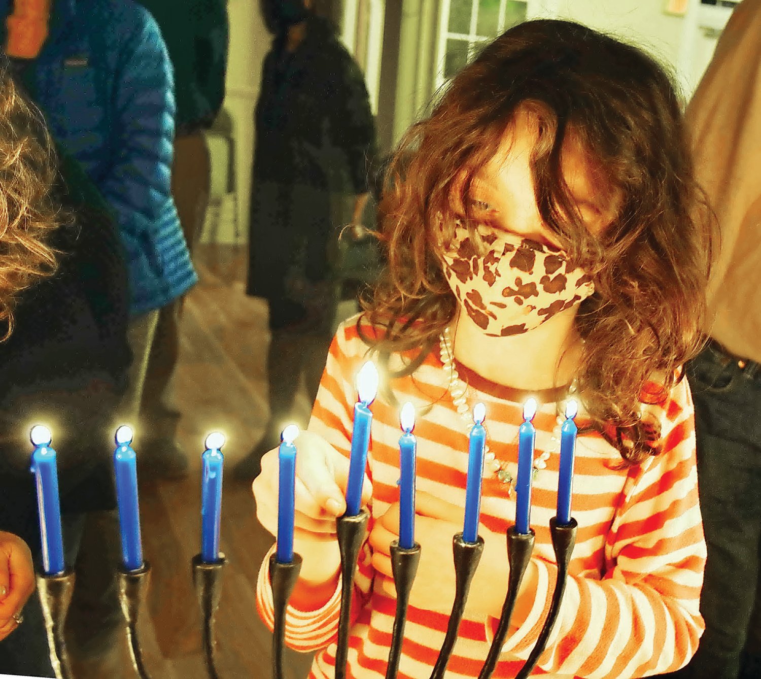 Dahlia Strumfels, 8, lights the candles on her menorah.