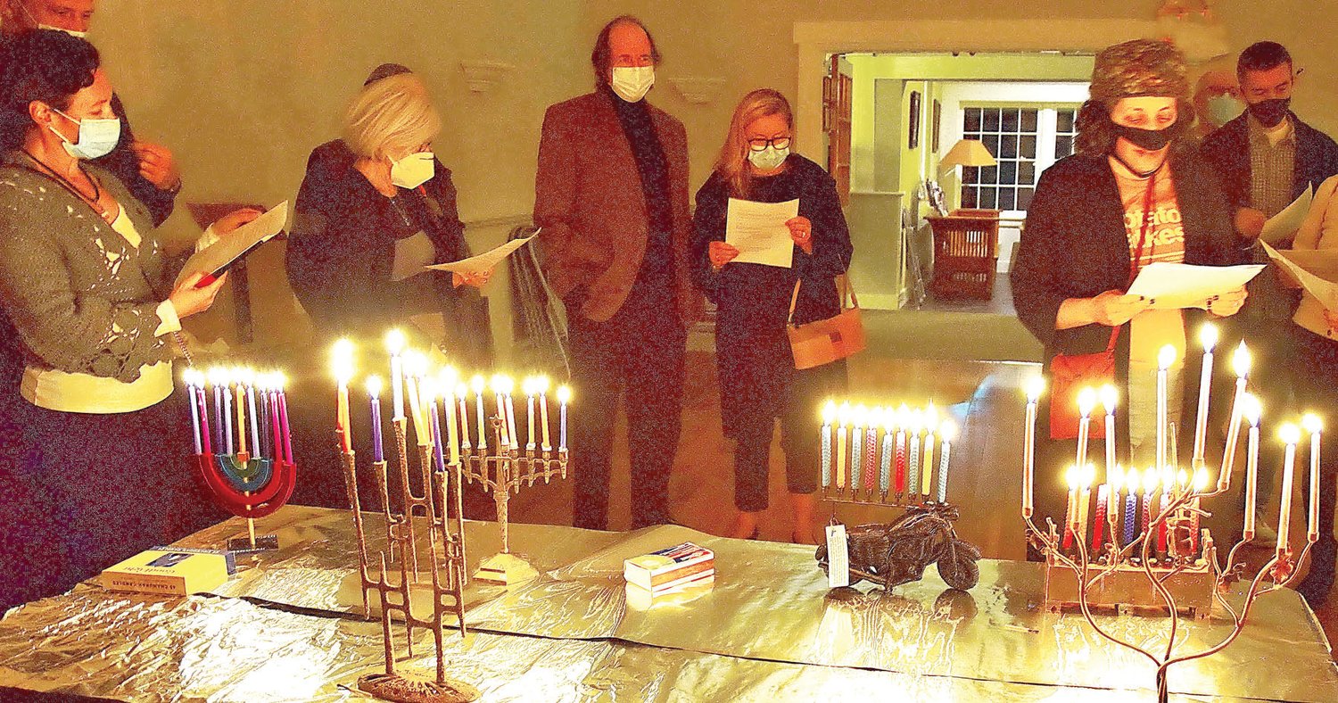 Members of the Kehilat Hanahar Shul, with Rabbi Diana Miller, right, recite prayers over all the lit menorahs.