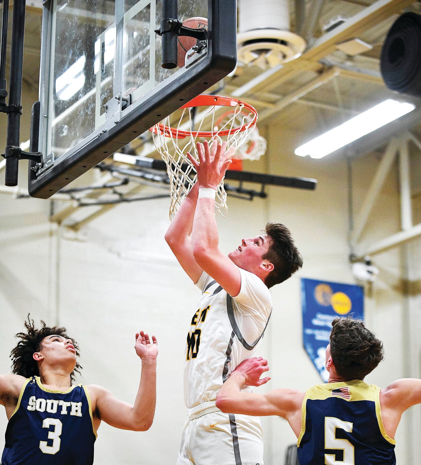 CB West’s John Lee gets up high for an easy layup against CR South’s Anthony Burns and Matt Robinson.