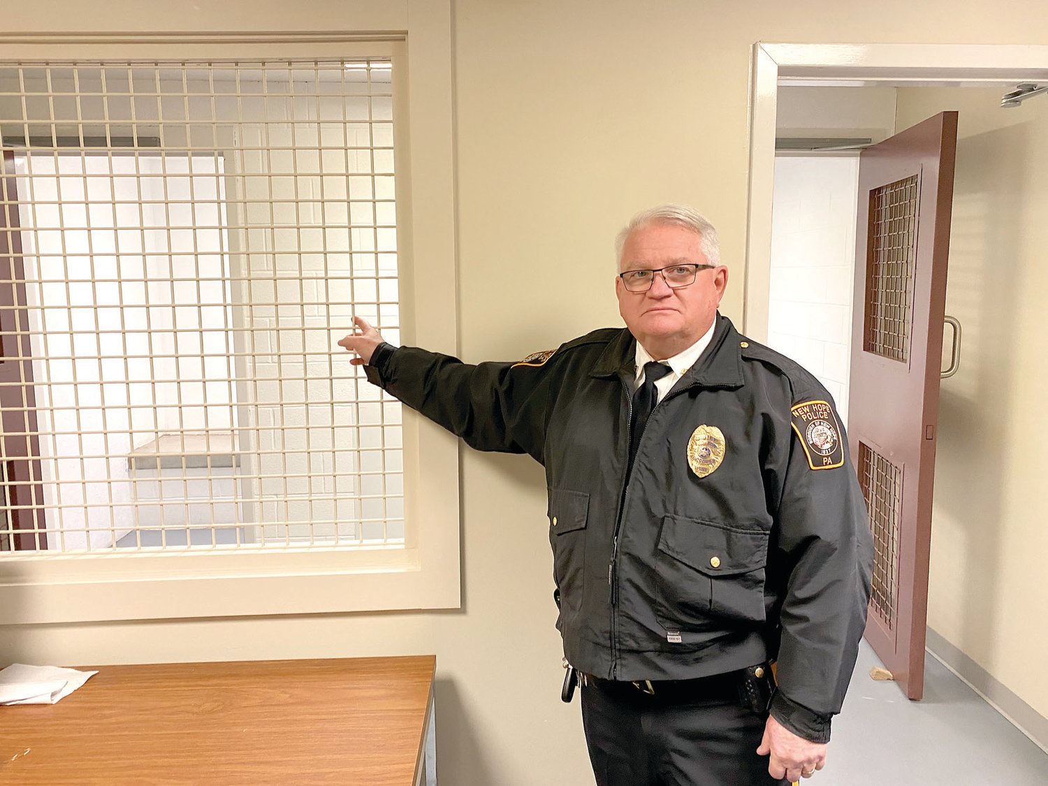 Chief Michael Cummings shows recently added transparent steel grating which replaced a solid wall in the New Hope Police office. State accreditation requires that prisoners be seen at all times.