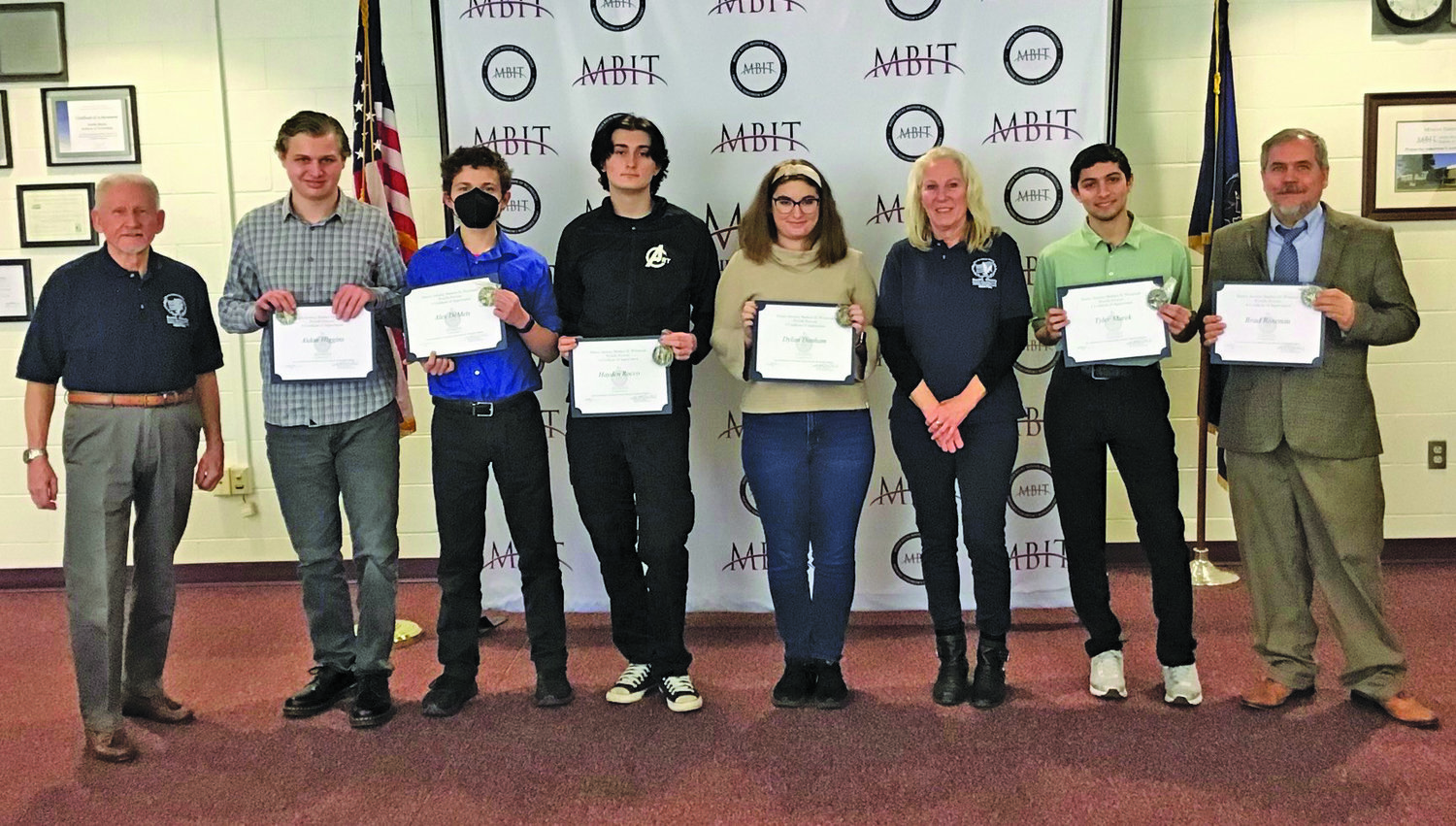 Carolyn Debuque and Elwood Hippel of the Bucks County District Attorney’s Office, Veterans Diversion Program, present student finalists with Certificates of Appreciation and the organization’s Mission Accomplished coin. From left are: Hippel, Aidan Higgins, Alex DeMets, Hayden Rocco, Dylan Dunham, Debuque, Tyler Marek and instructor Bradley Rosenau.