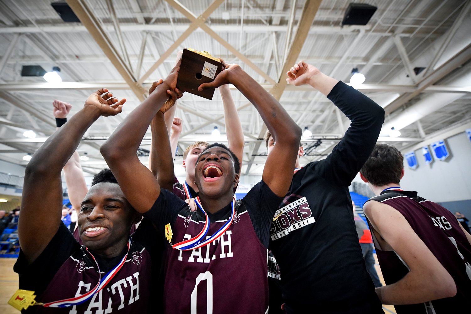 Faith’s Chris Evans, center, leads the celebration after getting the championship trophy.