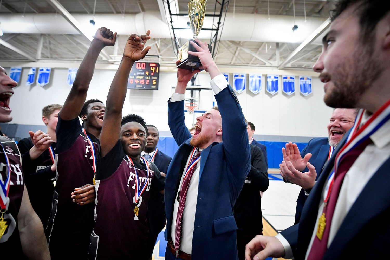 Faith Christian Academy boys basketball head coach Seth Brunner hoists the District One Class A trophy after the Lions defeated Plumstead Christian 41-34 in Saturday’s final at Bensalem High School. It was the second district championship of the day for Faith, whose girls basketball team captured its first district title earlier in the afternoon.