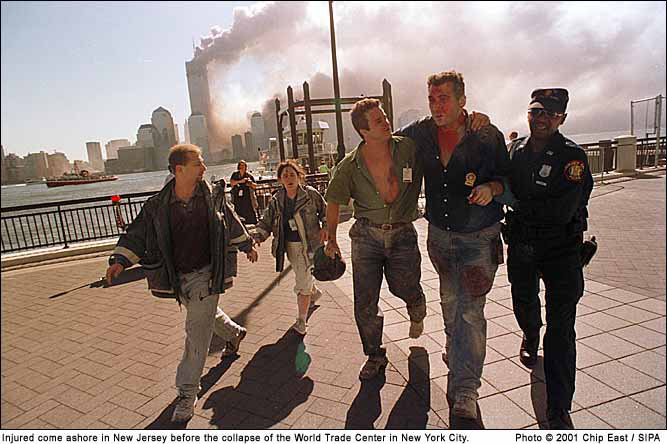 In this Sept. 11, 2001 photo taken by Chip East (SIPA), forensic biologist Mark Desire and his work partner, Ben, are escorted away from ground zero.