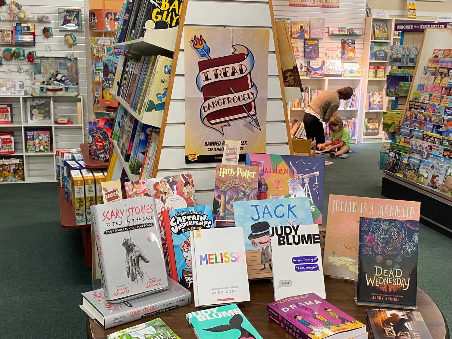 A children’s display holds works by Judy Blume, Alex Gino, and J.K Rowling. “I Read Dangerously” says the sign above the books.