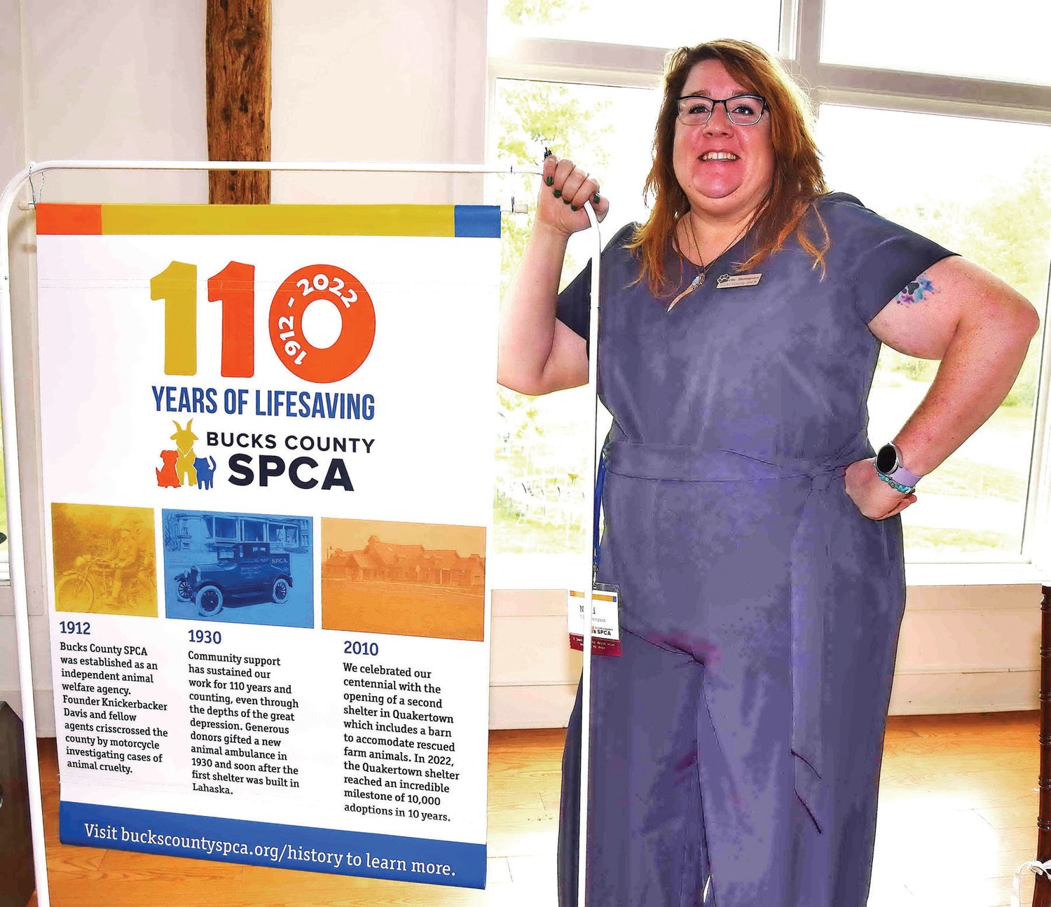 Staff member Nikki Thompson with a poster detailing the 110 years of Bucks County SPCA history.
