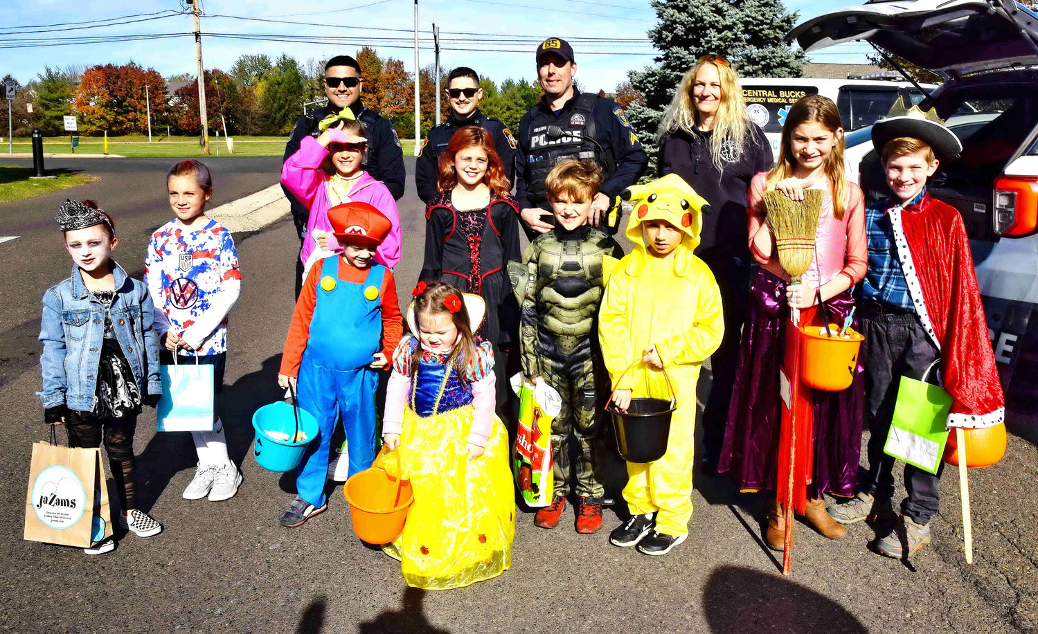 Police officers gather with children dressed in costumes.